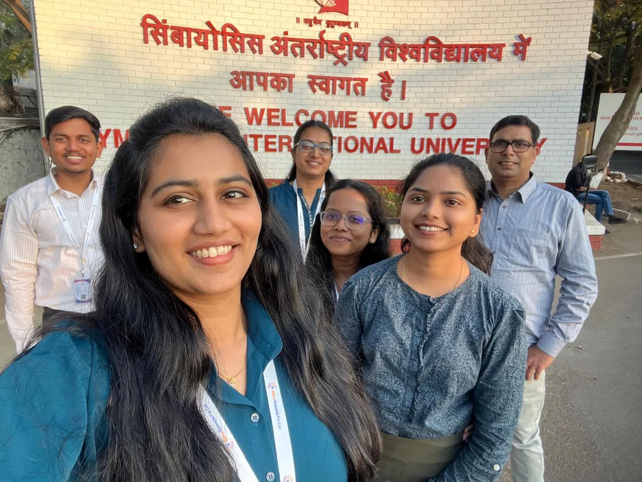 Six members of the SilicoScientia team standing together in front of the Symbiosis International University welcome sign