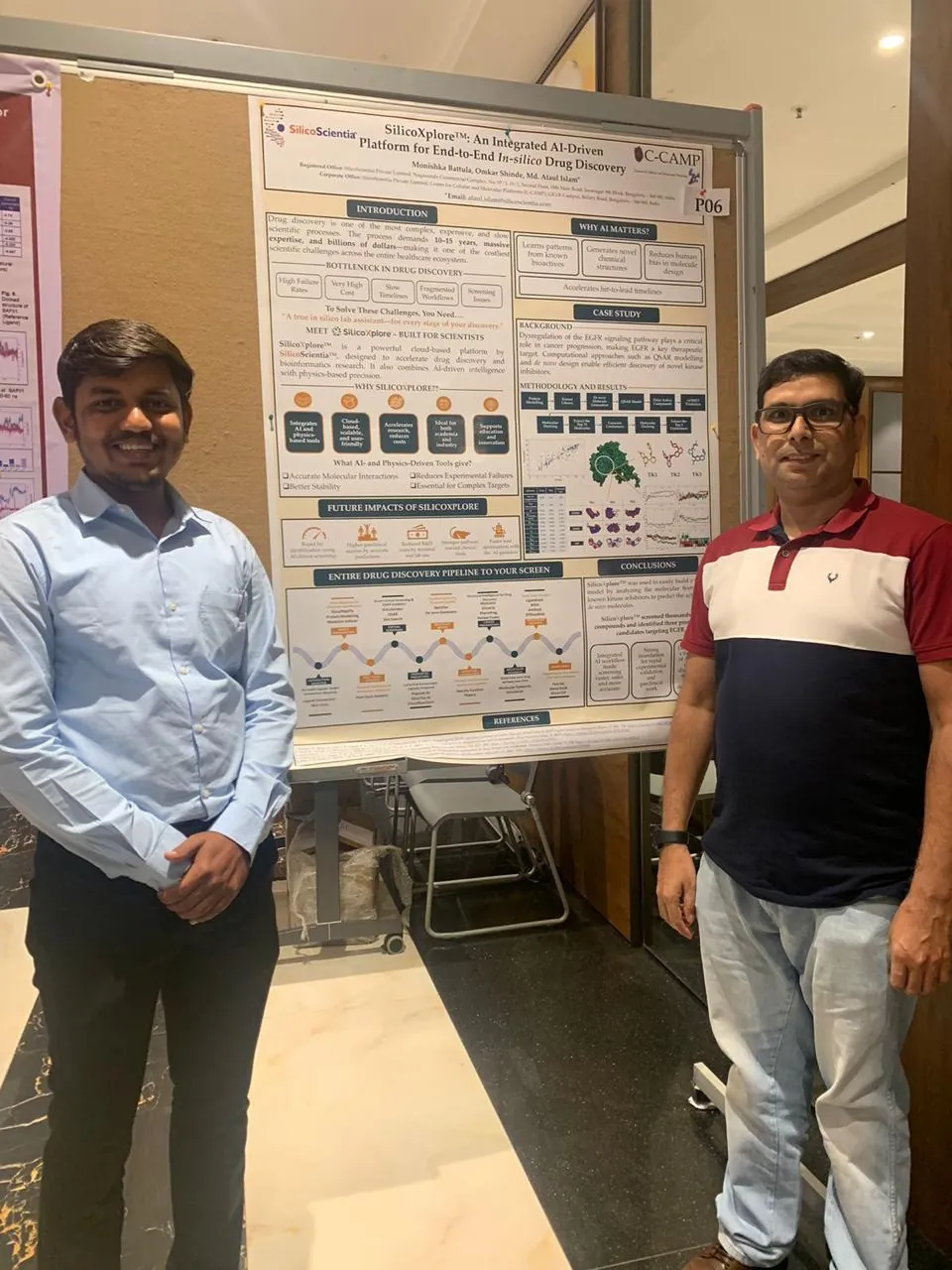 Two presenters standing beside a poster on an integrated AI-driven platform for in-silico drug discovery